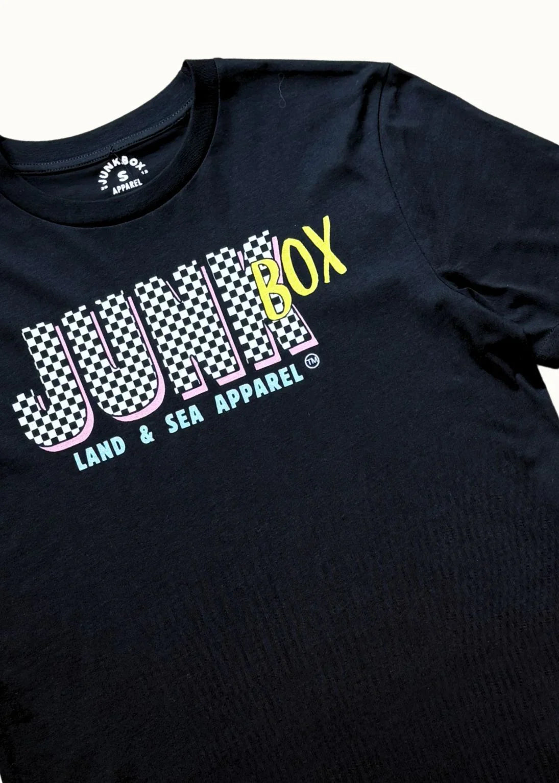 Black T-shirt with checkerboard 'JUNKBOX' text and 'LAND & SEA APPAREL' slogan print