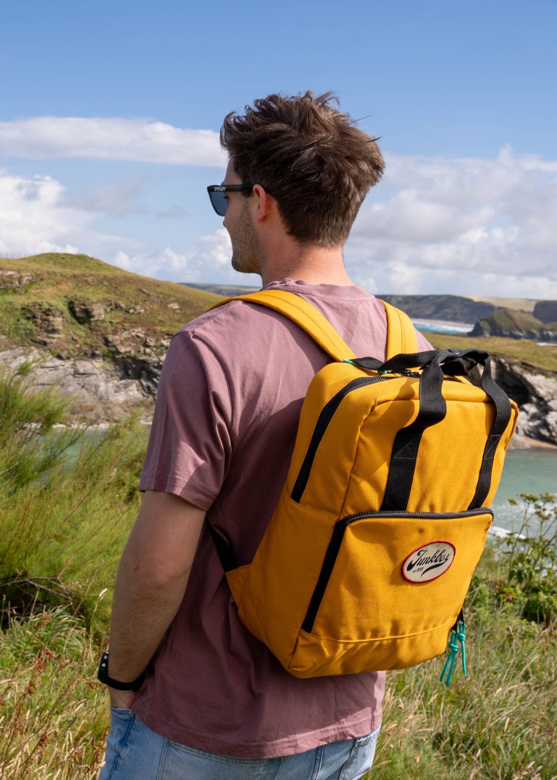 Man with a yellow backpack looking at a scenic landscape