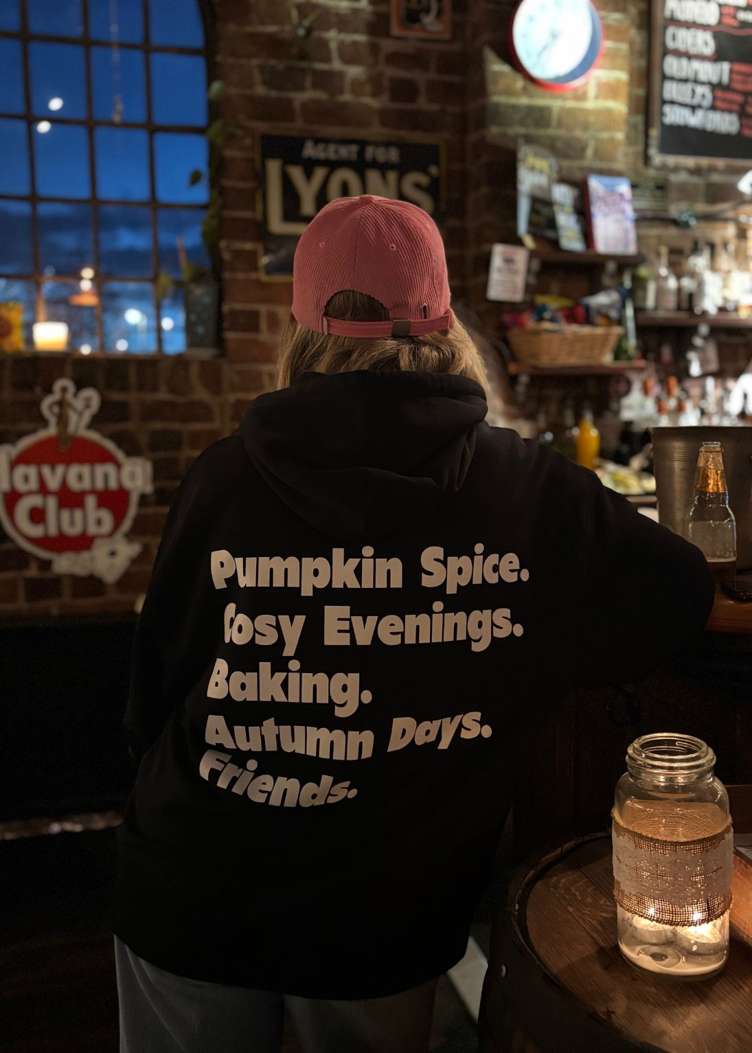 Person wearing a hoodie with text in a bar setting